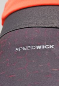Leggings da palestra viola con un motivo esagonale, caratterizzati da cuciture nere e una vita grigia. Logo "SPEEDWICK" ben visibile.