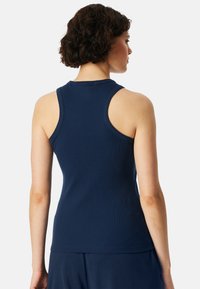 Navy blue sleeveless top made of ribbed fabric, featuring a round neckline and a fitted design. The back reveals a smooth texture.
