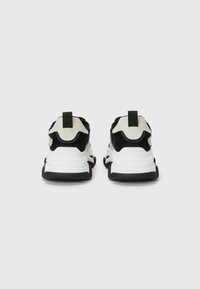 Black and cream athletic shoes with mesh and smooth panels. Features a thick white sole and pull tabs at the heel for easy wear.