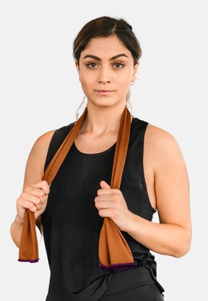 Brown training straps made from textured material, held in hands, with purple accents. Black sleeveless top with mesh design.