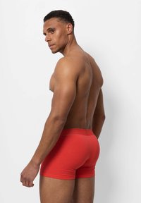 Shorts in cotone rossi, design aderente, lunghezza a metà coscia, texture liscia, con elastico in vita, modellati di lato.