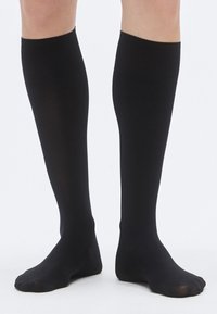 Crne čarape do koljena od glatkog, rastezljivog materijala s mat završetkom i otvorenim vrhom prsta, prikazujući elegantan, neprimjetan izgled.