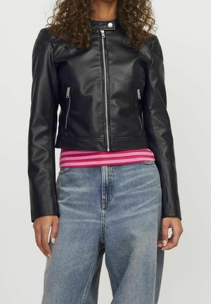 Femme portant une veste en cuir noire zippée, une chemise rayée rose et rouge, et un jean en denim bleu taille haute.