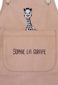 Light beige fabric apron with a large embroidered pocket. Features a simple giraffe design and the text "SOPHIE LA GIRAFFE" in dark blue.
