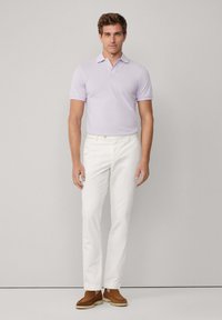 Světle fialová polo košile s klasickým límečkem, kombinovaná s bílými kalhotami a hnědými semišovými botami. Hladká látka, upravený střih.