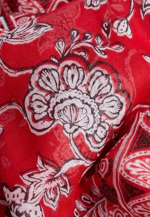 Tissu rouge avec des motifs floraux et cachemire blancs et noirs, présentant des pétales et des feuilles détaillés dans un design fluide et texturé.