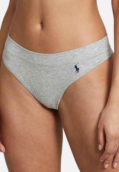 Donna che indossa un intimo bikini in cotone grigio chiaro con un piccolo logo ricamato blu scuro sul lato anteriore destro.