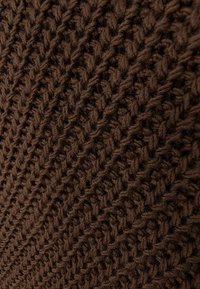 Brązowa dzianina z teksturowanym wzorem, charakteryzująca się wypukłymi, ukośnymi żebrowaniami oraz miękkim, grubym wyglądem.