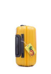 Maleta rígida amarilla con una superficie texturizada, mango negro y cremallera. Incluye una etiqueta de equipaje con un patrón de piña.