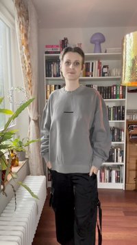 Grå sweatshirt med rundad halsringning och lös passform, med svart text "PELADON" på bröstet. Bärs med svarta cargobyxor.