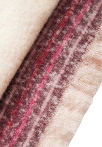 Coperta di lana con una morbida base crema, caratterizzata da motivi geometrici rosa e viola scuro, superficie texture e bordi sfrangiati.