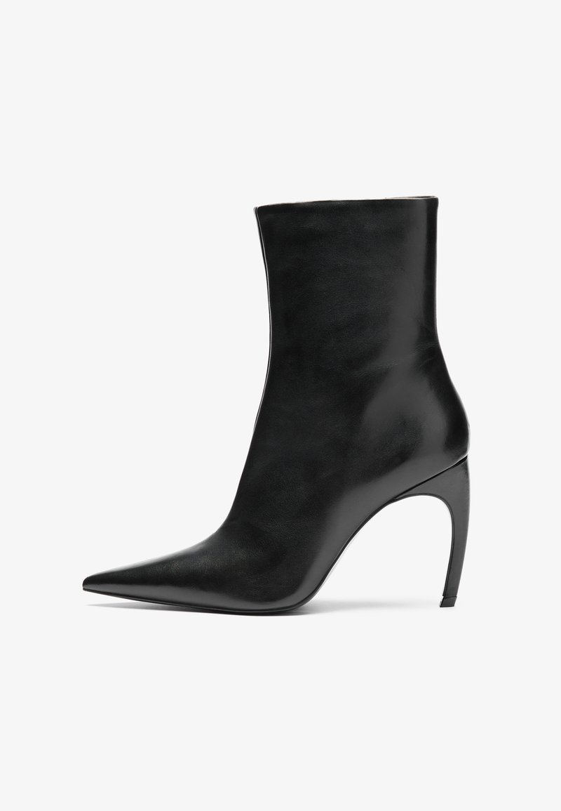 Stivaletto in pelle nera con punta appuntita e alto tacco a stiletto. La texture liscia e il design minimalista enfatizzano l'eleganza moderna.