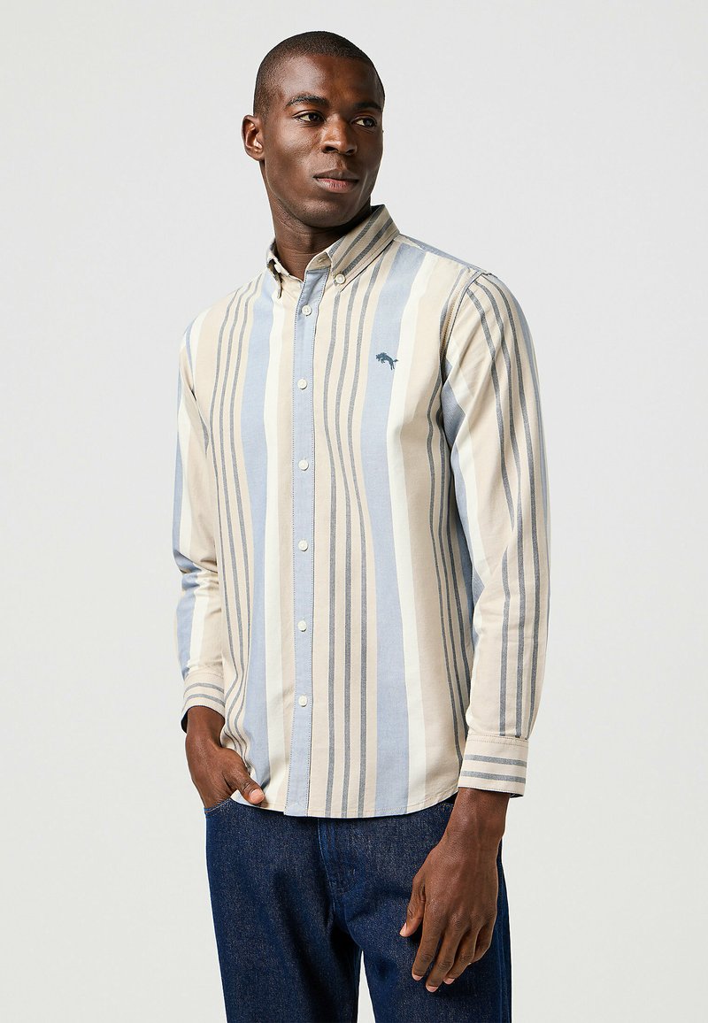Camisa de botones con rayas verticales en beige y azul claro, hecha de algodón suave y con un pequeño logo bordado en el pecho.