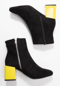 Černé antekové ankle boots s špičatou špičkou, bočním zipem a kontrastním žlutým blokovým podpatkem. Hladký povrch a elegantní design.