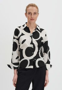 Camicia a maniche lunghe bianca e nera con grandi motivi circolari, con colletto classico, realizzata in un tessuto morbido.