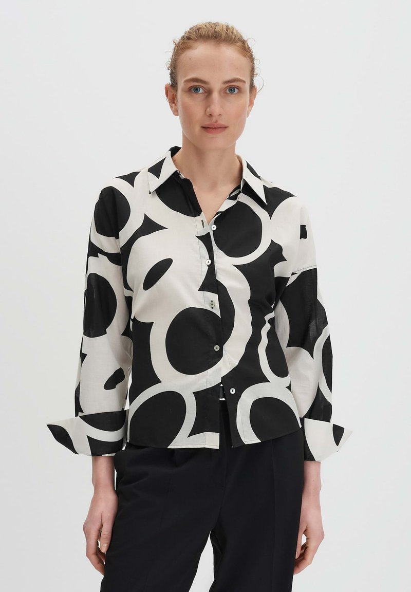 Camicia a maniche lunghe bianca e nera con grandi motivi circolari, con colletto classico, realizzata in un tessuto morbido.