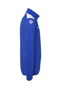 Blauwe sportieve jas met een ritssluiting aan de voorkant, witte schouderaccenten en logo. Heeft een staande kraag en twee zijzakken.