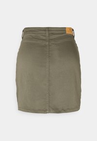 Jupe en denim vert olive avec une coupe ajustée, dotée d'une poche arrière, de coutures visibles et d'une étiquette en cuir tan de marque au niveau de la taille.