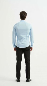 Chemise bleu clair à manches longues avec des détails de boutons, forme ajustée et texture lisse ; associée à un pantalon noir ajusté et des chaussures noires.
