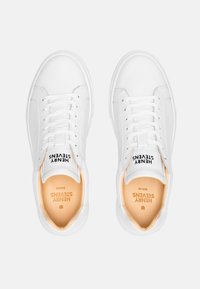 Weiße Ledersneaker mit glatter Textur, abgerundeter Zehenpartie, flachen Schnürsenkeln und beigen Innensohlen. Mit Markenlogo auf der Zunge und Innensohle.