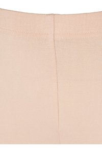Close-up of beige stretchy fabric with visible seam and elastic waistband edge.