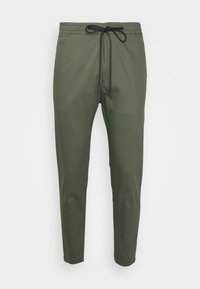 Olijfgroene casual broek met elastische tailleband en zwarte trekkoord, taps toelopende benen, tegen een witte achtergrond.