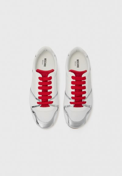 Pantofi sport albi cu șireturi roșii, accente metalice argintii, o textură netedă și un design curbat, având detalii cu logo în interior.