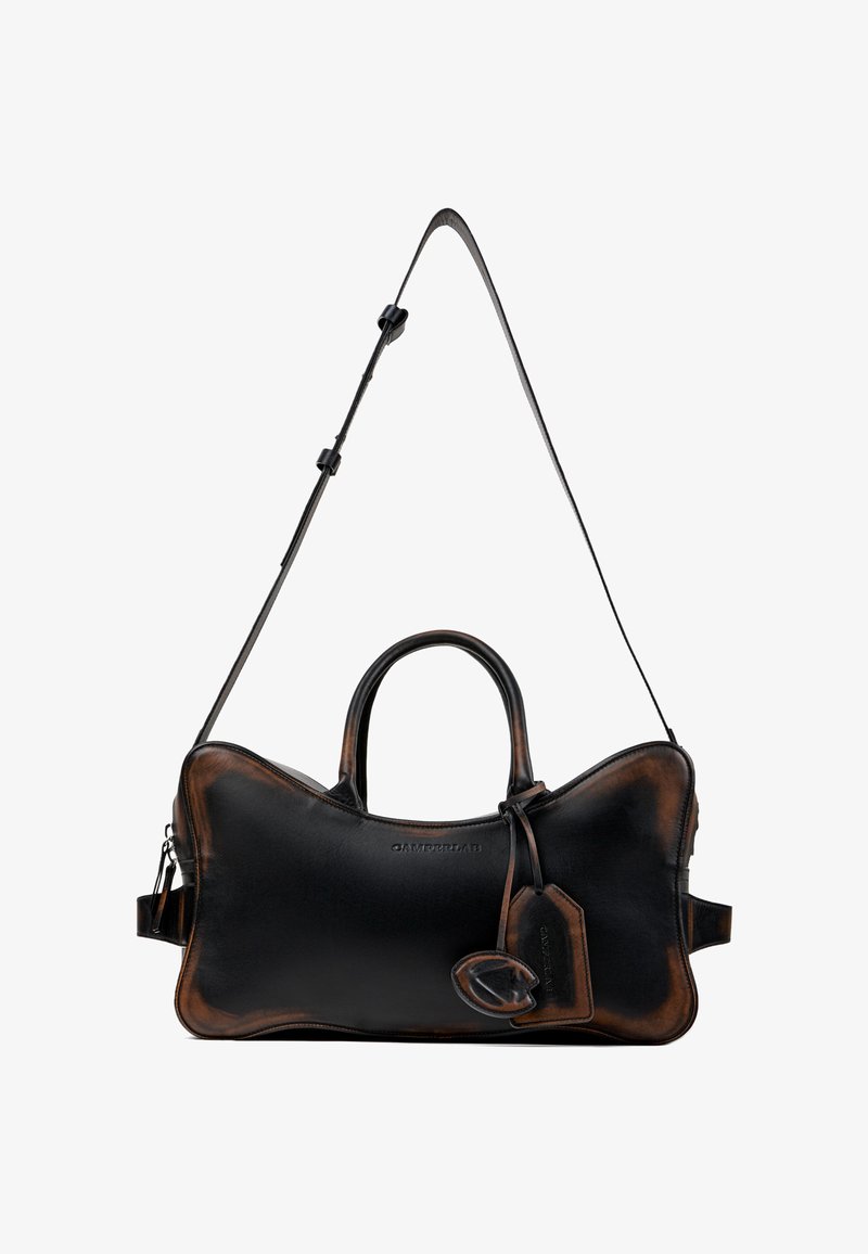 Sac à main en cuir noir avec bords marron foncé, poignées supérieures, sangle d'épaule réglable et étiquette de bagage attachée.