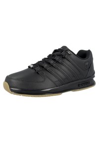 Black athletic shoe made of synthetic leather, featuring six black lace eyelets, textured surface, and a rubber outsole with light brown accents.