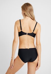 Schwarzes Bikini-Set mit einem BH mit Rückenverschluss und einer Hose in mittlerer Höhe. Glatte Textur, verstellbare Träger und minimalistisches Design mit metallischen Akzenten.