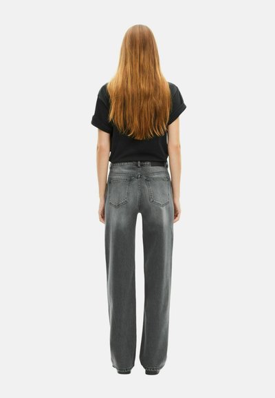 Jeans de mezclilla grises de pierna ancha con un acabado desgastado, de cintura alta y cinco bolsillos, combinados con una camiseta negra de manga corta.