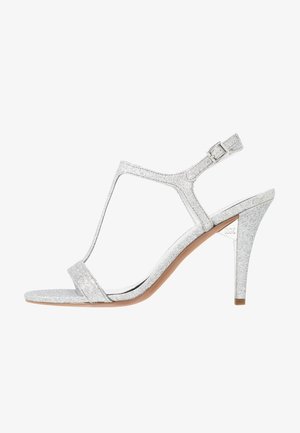 Zilveren glinsterende hoge hak sandaal met een T-riem ontwerp, verstelbare enkelgesp en een slanke stilettohak. Gladde zool met een subtiele verloopkleur.