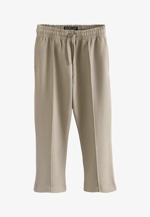 Beige sportsbukser lavet af blødt stof. Har en elastisk talje med snor, sidelommer og en tapered ben-design.