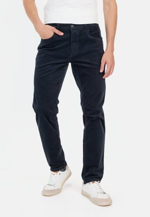 Donkerblauwe corduroy broek met een regular fit, voorzien van een knoopsluiting en zijzakken, gecombineerd met witte sneakers.