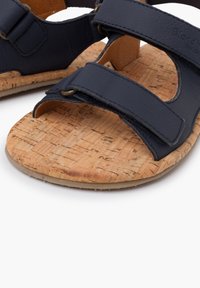 Modré kožené sandály s korkovými stélkami, vybavené dvěma nastavovacími popruhy a metalovými akcenty. Rovná podrážka s texturovaným korkovým povrchem.
