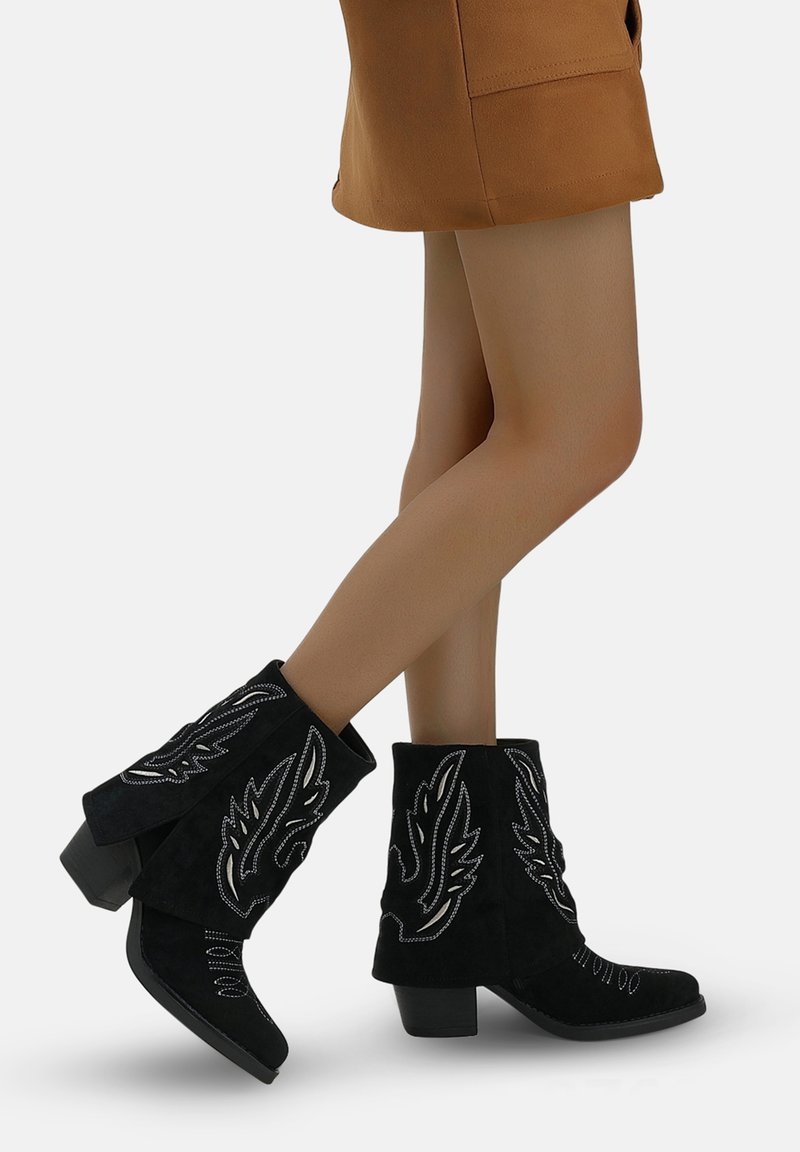 Botas de tobillo de ante negro con patrones de alas bordadas, un tacón cuadrado y un diseño de flecos abierto en la parte superior.