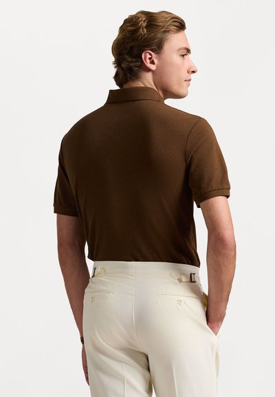 Cămașă polo scurtă maro, cu un design tricotat texturat, asociată cu pantaloni crem, care au nasturi laterali ajustabili și buzunare la spate.