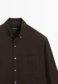 Camicia button-up marrone scuro con colletto appuntito e una singola tasca sul petto, esposta su uno sfondo bianco.
