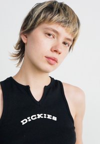 Zwarte mouwloze top met een geribbeld textuur, voorzien van een V-hals en het witte "DICKIES" logo op de borst.