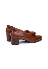 Chaussures à talon bas en cuir marron pour femmes, avec une texture en faux crocodile à l'arrière et un petit emblème doré sur le côté.