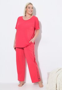 Katoenen loungewear set in levendig koraal, met een losvallend top met gestikte details op de mouwen en bijpassende ontspannen broek met zijzakken.