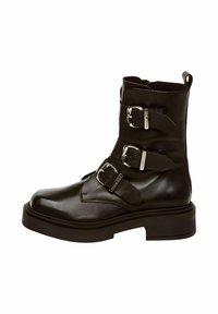 Botas de cuero negras hasta el tobillo que cuentan con tres hebillas metálicas ajustables, una punta redonda y una suela gruesa negra con detalles texturizados.