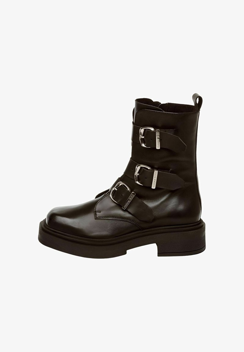 Mustad mustad nahast ankle saapad, millel on kolm reguleeritavat metallist pandlat, ümmargune varvas ja paks must solk, millel on tekstuuriga detailid.