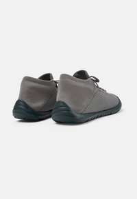 Sneaker grigie con una toma in maglia testurizzata e suola in gomma scura. Presentano un design a taglio basso e chiusura con lacci per una vestibilità sicura.