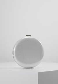 Okrąła srebrna kopertówka wykonana z błyszczącego materiału o gładkiej fakturze, z prostym prostokątnym zapięciem na górze.