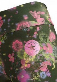 Leggings con motivo floreale in verde scuro con accenti rosa, viola e giallo. Presentano un patch rotondo del logo Converse rosa sulla vita.