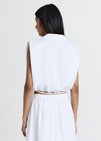 Top bianco senza maniche con colletto e vita elastica. Tessuto liscio con una vestibilità rilassata e ampia, che mette in risalto il design sul retro.