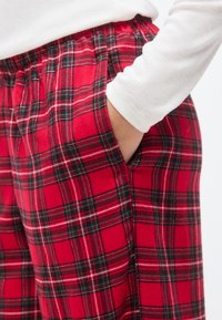 Κόκκινο καρό παντελόνι από μαλακό ύφασμα, με ελαστική μέση με κορδόνι και πλαϊνές τσέπες, με ασπρόμαυρα καρό σχέδια.