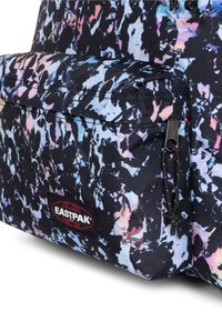 Zaino in tessuto nero con motivo astratto colorato. Presenta una tasca frontale con chiusura a zip e patch logo Eastpak. Superficie strutturata.