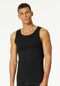 Black cotton tank top with a round neckline, sleeveless design, and fitted silhouette, displayed on a model against a plain background.